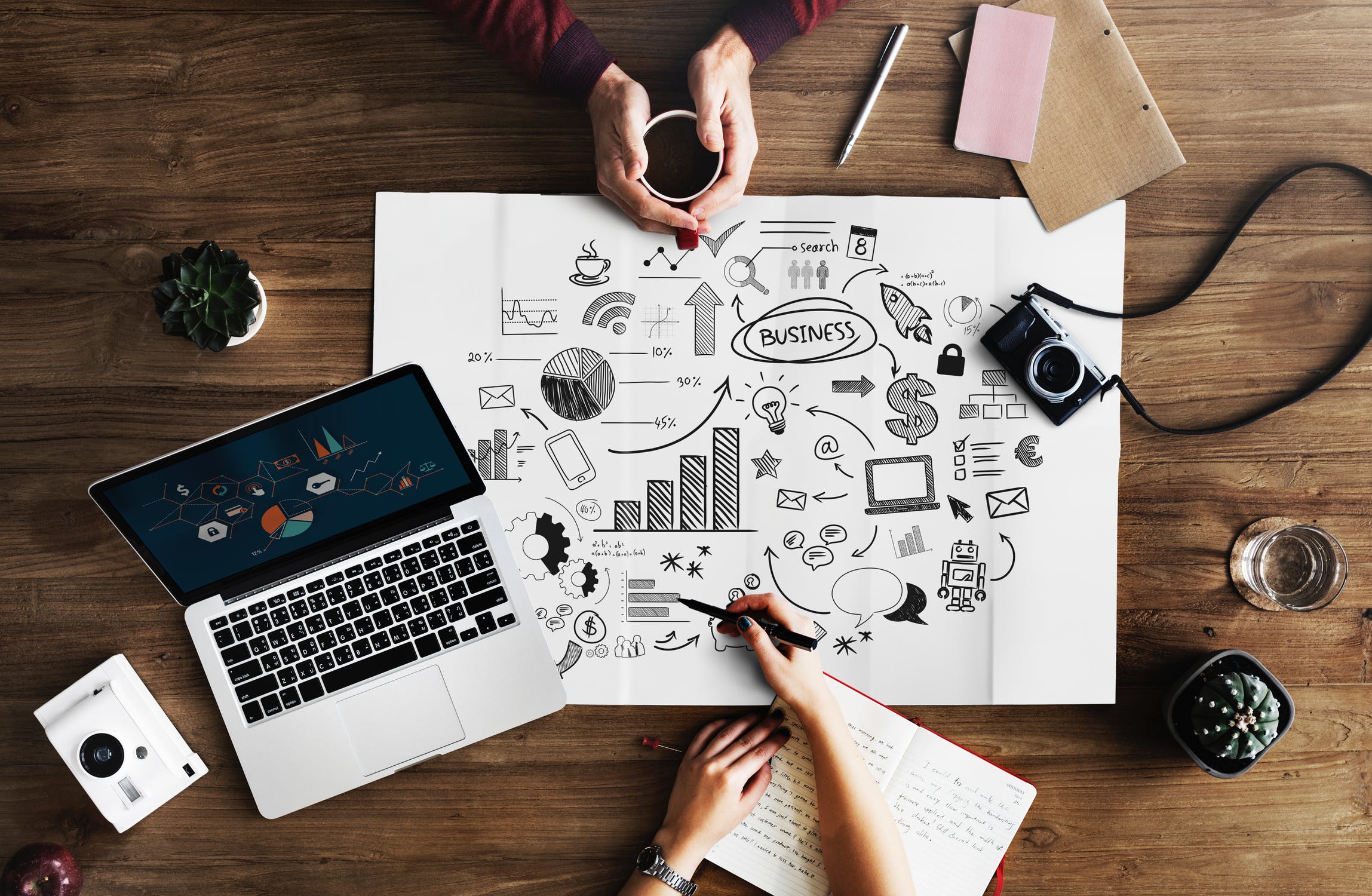 A couple of people drawing business imagery on a poster board