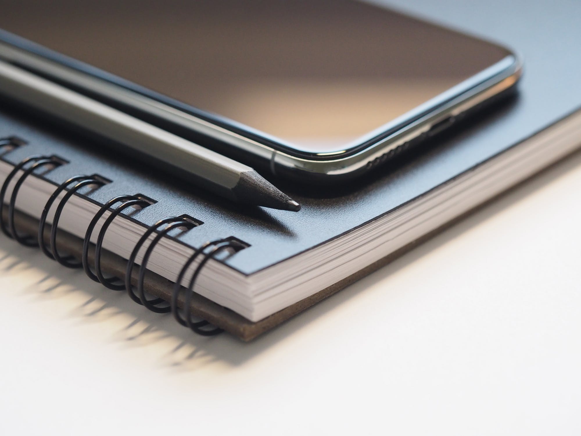 A phone and a pencil laying on top of a notebook